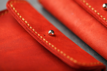 Purse made of genuine red leather, handmade on a dark background. Stitched seams.