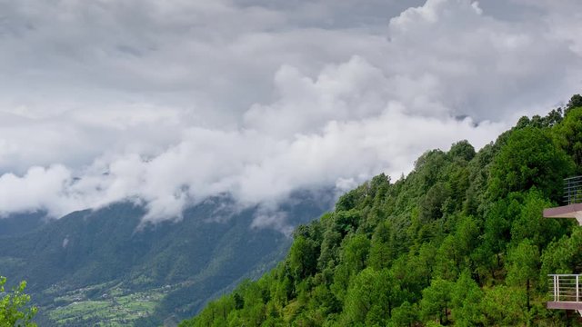 Timelapse of fluffy white grey clouds rolling over the green tree covered hill sides shot in McLeodganj himachal pradesh india