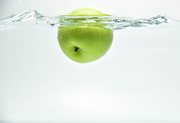 Green apple in the  splash water and air bubbles  on white background