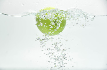 Green apple in the  splash water and air bubbles  on white background