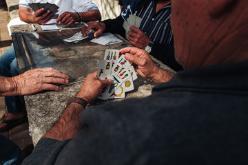 MARTINA FRANCA, ITALY / SEPTEMBER 2019:  Old mens playing traditional card game in the parc - obrazy, fototapety, plakaty