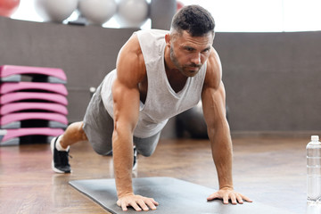 Portrait of a fitness man doing planking exercise in gym.