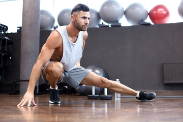 Naklejka premium Man at the gym doing stretching exercises on the floor.