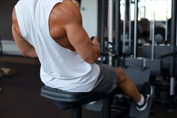 Fit and muscular man using rowing machine at gym. Back view