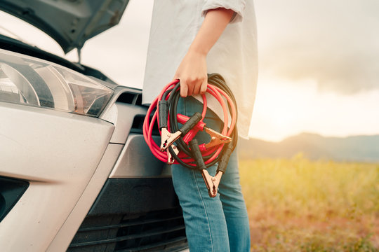 Close up Woman connecting battery cable copper wire for jumper repair and maintenance electric of engine car problem, broken her self service transportation, Vehicle stop engine between travel