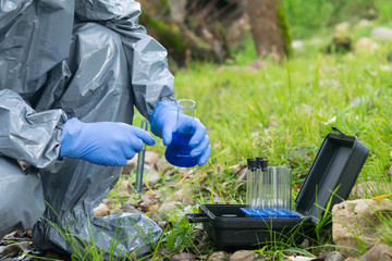 a man in a protective suit analyzes water in a mobile laboratory using special reagents