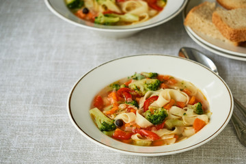 Soup with fresh vegetables and noodles in a white bowl 