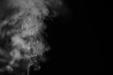 White smoke on a black background. Texture of smoke. Clubs of white smoke on a dark background for an overlay