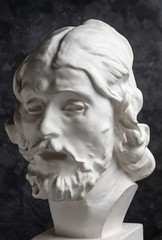 Gypsum copy of ancient statue John the Baptist head on dark textured background. Plaster sculpture...