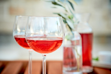 two glasses of rose wine with  olives against blue water on a pier..