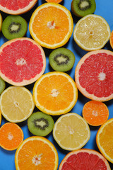 Fresh summer fruits on blue background. Healthy food concept. Flat lay. Tropical summer mix grapefruit, orange, mandarin, kiwi, lemon