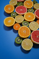Fresh summer fruits on blue background. Flat lay. Tropical summer mix grapefruit, orange, mandarin, kiwi, lemon