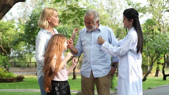elderly couple patient and daughter talking and examining  with Asian medical doctor woman. Physician personal of family at  garden park in hospital  . Shake hands . good byb . outdoors. girl.