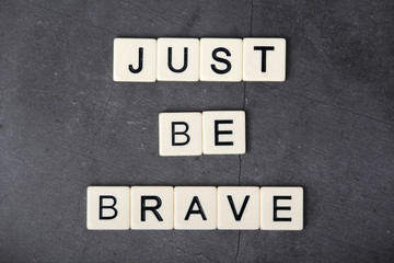 A motivational quote Just be brave formed with tile letters
