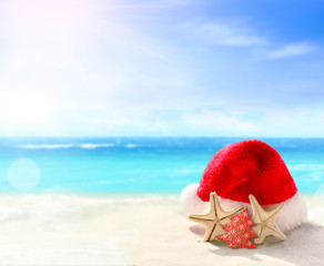Fototapeta na wymiar Christmas holidays concept. Santa claus hat on summer sand beach.
