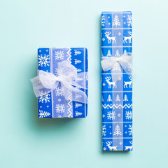 wrapped Christmas or other holiday handmade present in paper with white ribbon on blue background. Present box, decoration of gift on colored table, top view