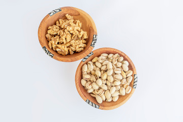 Chestnuts and pistachios in wooden bol as appertiser with drinks against a white background