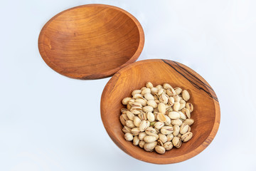 Pistachios in wooden bol as appertiser with drinks against a white background
