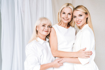 elegant three-generation blonde happy women in total white outfits