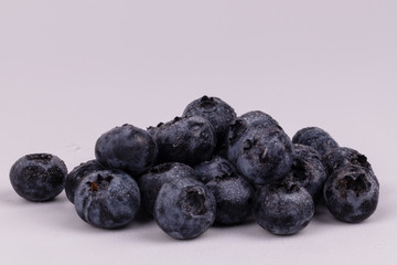 Side front view of a pile of wet blueberries on a white background