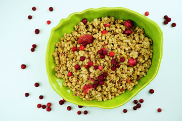 Muesli with strawberry and cranberry in green bowl on white background