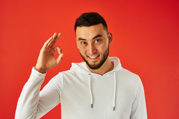 Handsome Kazakh man toothy smiles on red background shows 