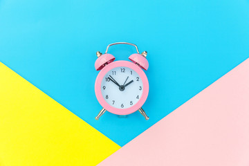 Ringing twin bell classic alarm clock isolated on blue yellow pink pastel colorful geometric...