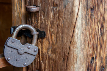 Rusty padlock on a door close-up. An old castle hangs on a wooden door.