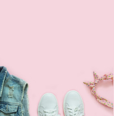 Denim vest, white sneakers and hair band on a pink background. Flat lay on the theme of travel, active lifestyle. Top view. Place for text.