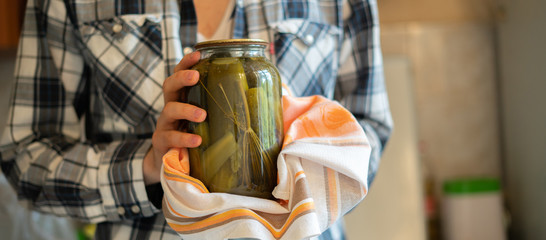 ready for winter season, person hand holding the pickled tomatoes and cucumbers in jar