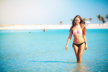 Obraz premium Travel vacation wallpaper - Beautiful young pretty blonde girl in white bikini with white sand on her perfect sport sexy body relax in sea of white sand paradise tropical Maldives beach at sunny day