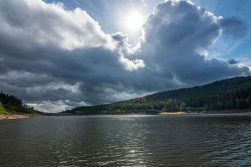 The Schwarzenbachtalsperre in Black Forest, Germany, with many clouds and some colored trees in the fall. 