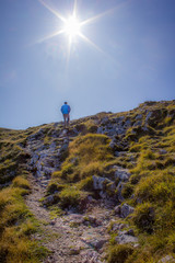 Mann auf einem Berg steigend von hinten mit Sonne als Stern
