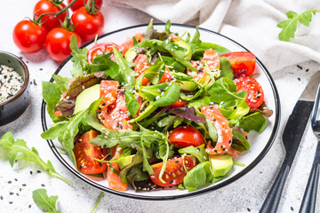 Salmon salad with green leaves on white.