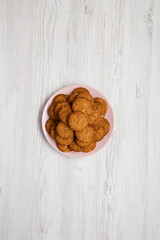 Cereal cookies on a pink plate on a white wooden background, top view. Flat lay, overhead, from above.