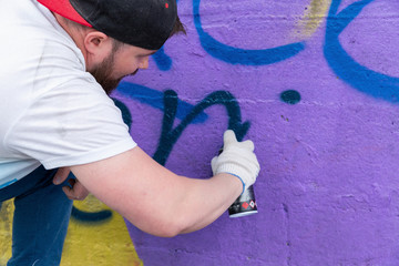 Graffiti artist painting with aerosol spray bottle