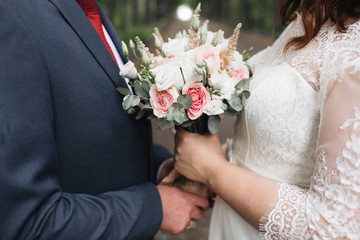 The bridegroom at the wedding walk gently hugs the bride's waist. Beautiful wedding bouquet color luxury