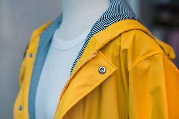 Closeup of yellow rain coat on mannequin in fashion store showroom