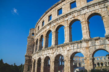 Fototapeta premium Close up picture of the colosseum in Pula Croatia with blue sky and small windows view from there, local and famous landmark in city with big history, wallpaper for greeting card from vacation