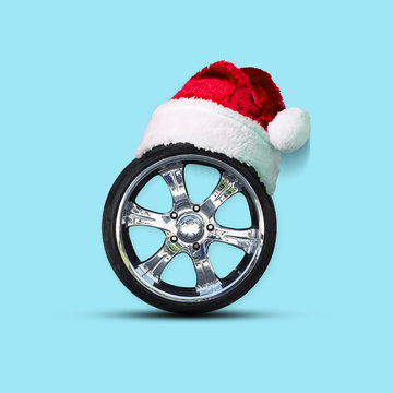 Car wheel with a cap of Santa Claus. Isolated on a blue background. Christmas background.