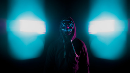 Chico con mascara de luces fondo negro y luces azules a los lados