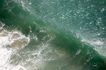 Beautiful crushing wave of Atlantic ocean, captured during the walk along the sandy beach in Nazare, Portugal
