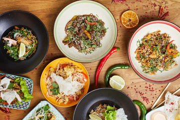 Top view closeup of beautiful Asian dishes set on wooden table decorated with hot red pepper and lime, copy space