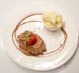 Chocolate cream cake with strawberry and sauce, vanilla ice cream, on white plate