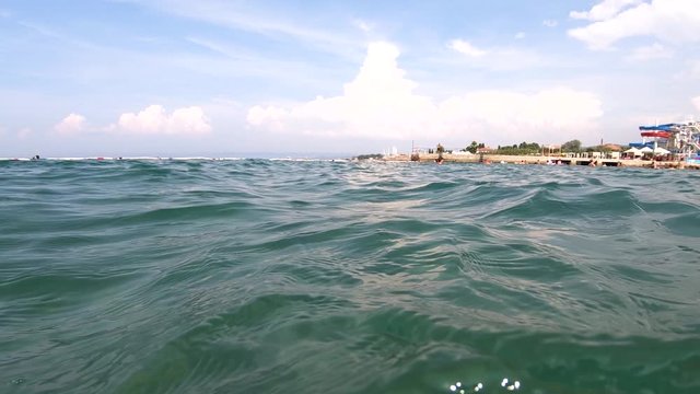 Slow motion surface sea water waves with tourists swimming