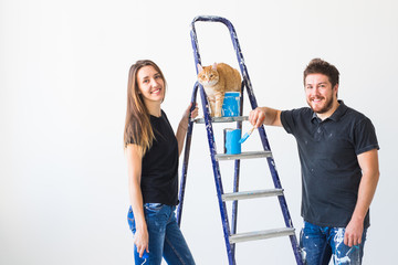 Teamwork and repair concept - young couple with cat doing a renovation in new apartment