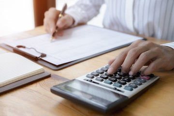 Close-up of businessman hand using calculator to calculate business data, accountancy document at home office.