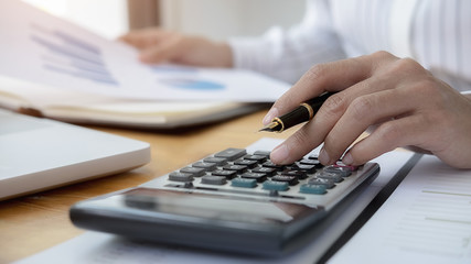 Close-up of businessman hand using calculator to calculate business data, accountancy document at home office.