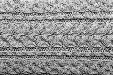 Gray knit fabric background with horizontal Irish cable pattern, wool texture in soft tones