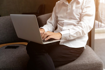 Close-up of male hands using laptop at modern office, man's hands typing on laptop keyboard in relax time morning. Side view of businessman using computer in cafe.